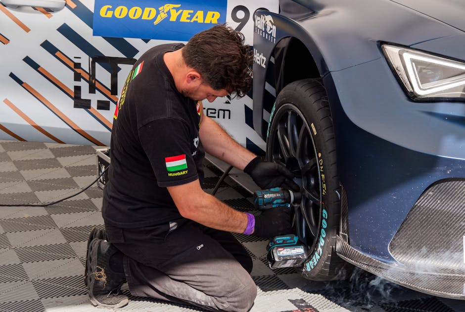 Mechanic fixing a car tire in a service station using power tools. Professional car maintenance.